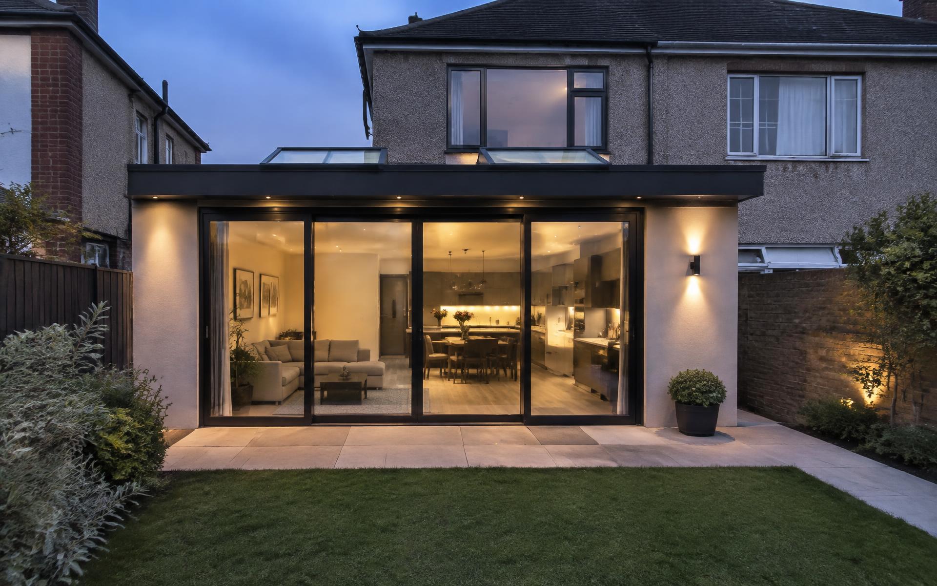 Modern rear home extension in Dublin with large glass doors lit at dusk